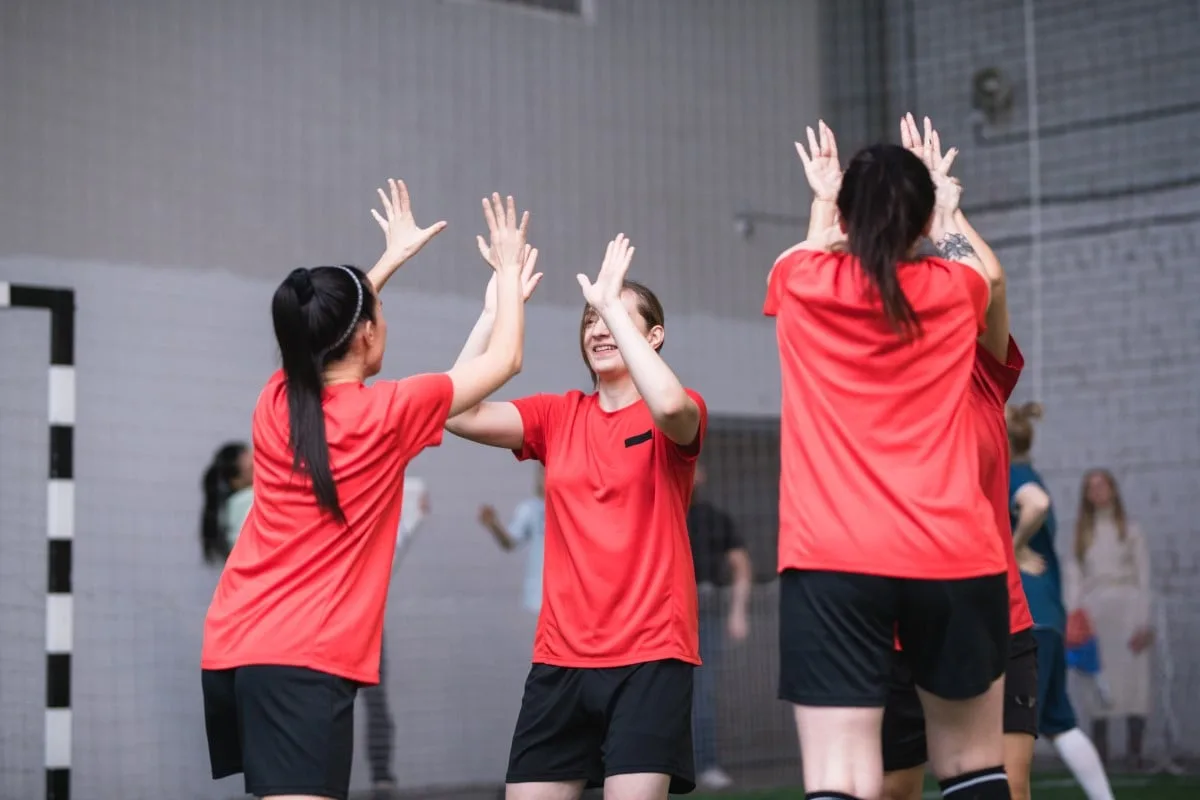 Team Of Active Girls In Sports Uniform Expressing Triumph By High Five Gesture